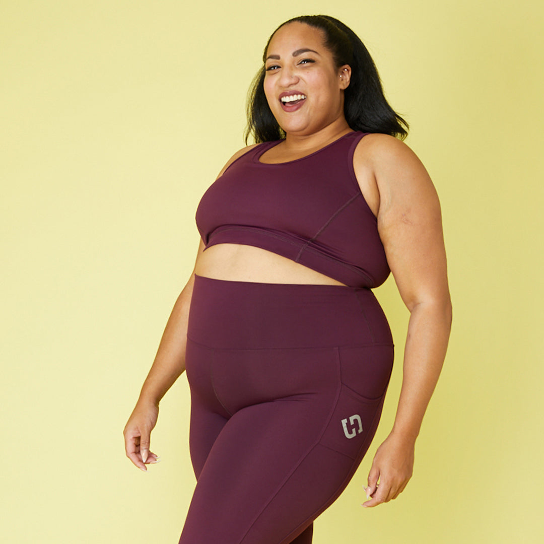 Plus size woman wearing Superfit Hero's sports bra and leggins in color Burgundy.