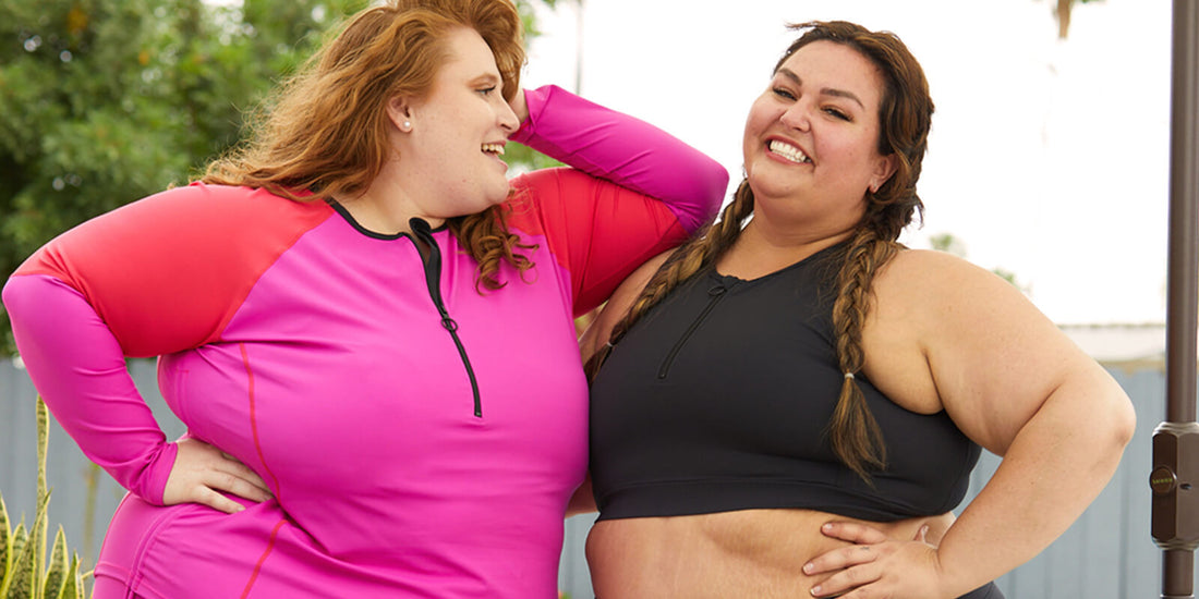 Two plus size models smile by the pool in their Superfit Hero swim tops