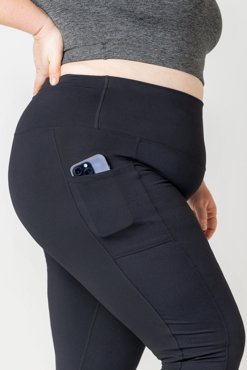 Detail shot of large pocket on side of Superfit Hero leggings with a full size phone in the pocket.