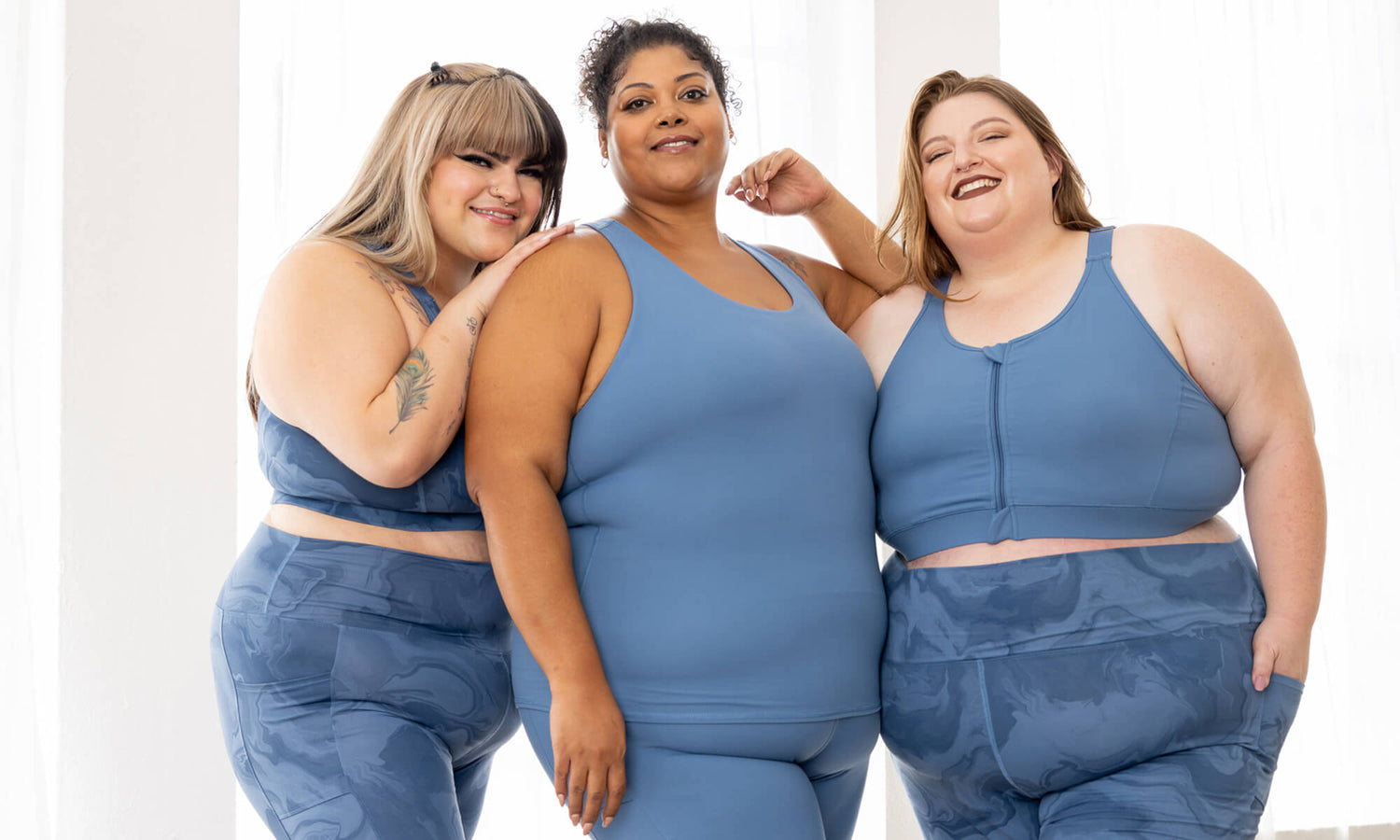 Three plus size models welcome you to the Superfit Hero Community. They're wearing Moonlight Blue and Moonlight Marble Zip Front Sports Bras & Shelf Bra Tank Tops.