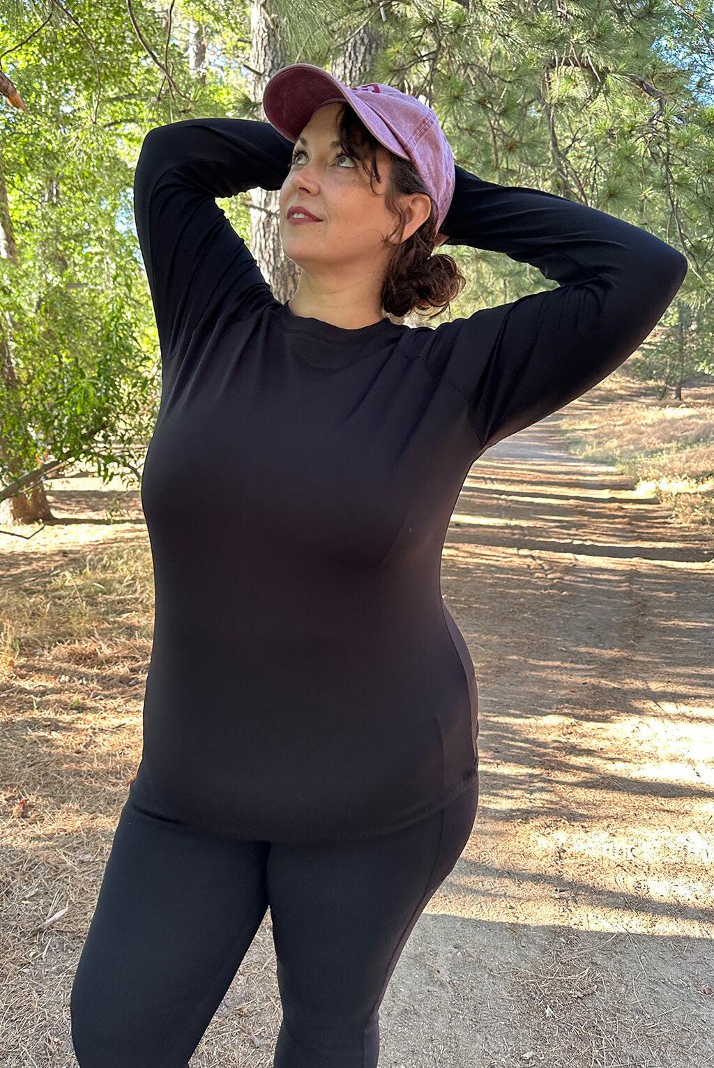Plus size model with arms behind her head wearing long sleeve compression top.