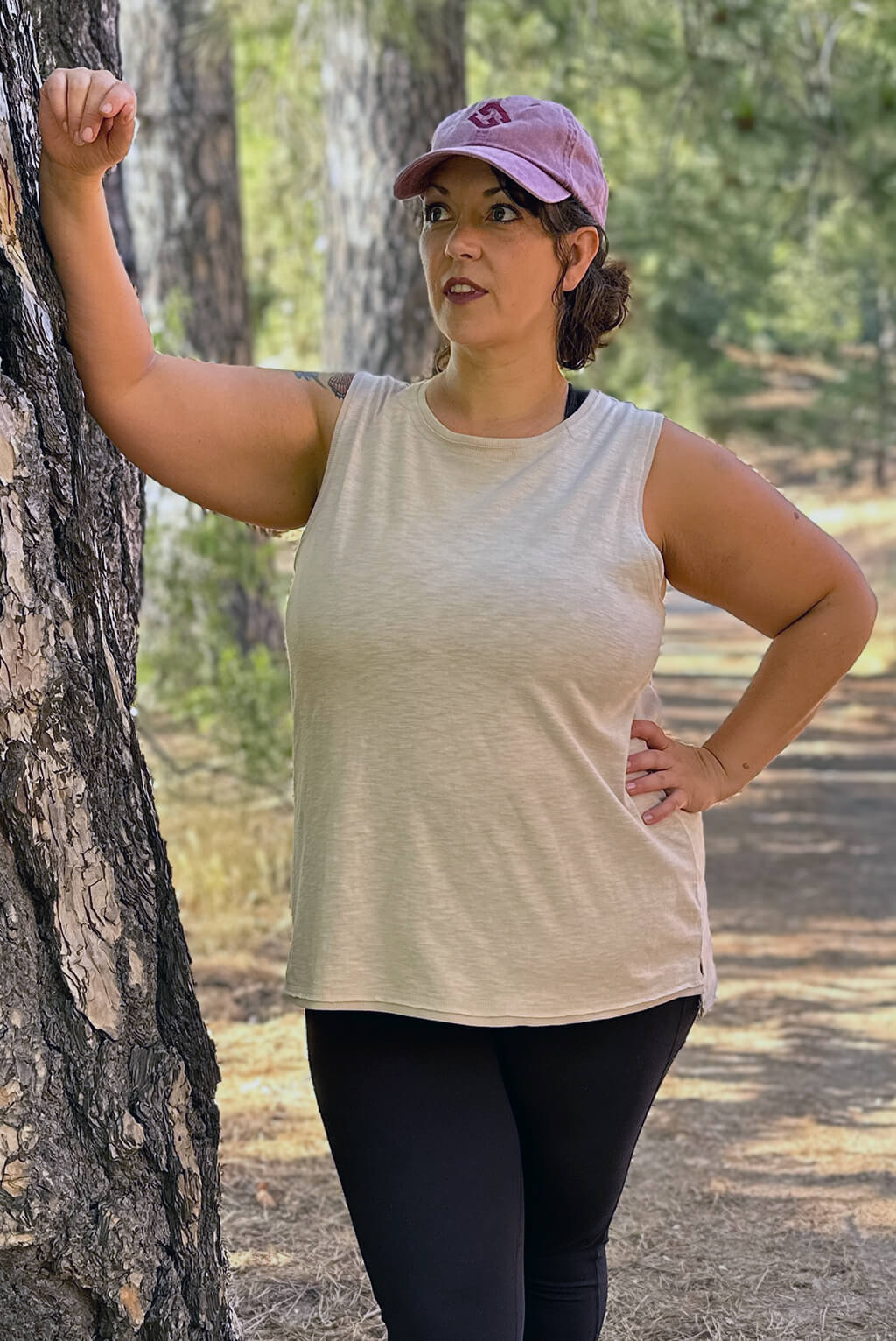 Plus size model leans on tree and looks off into distance wearing Textured Muscle Tank.